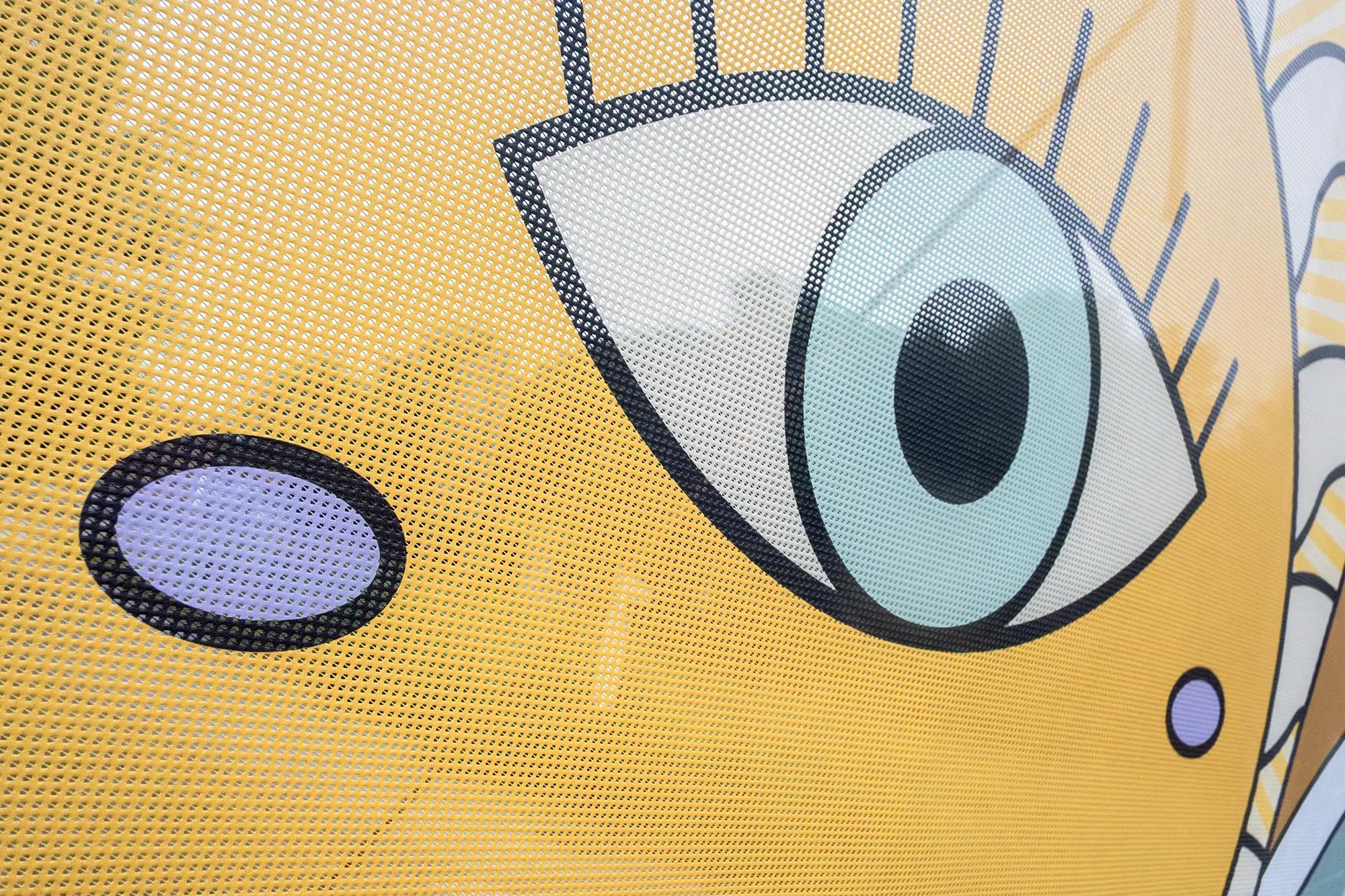 Detalle de ojo en cartel amarillo con perforaciones.